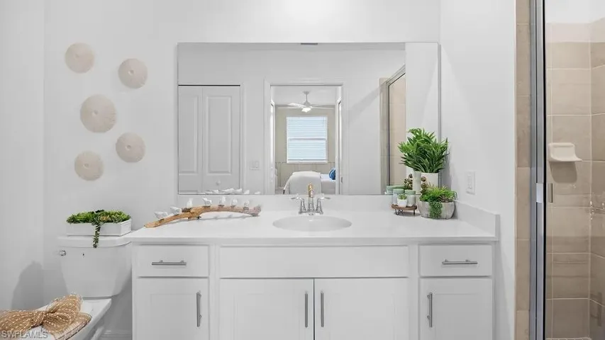 Ensuite bathroom featuring vanity, a stall shower, a closet, and ceiling fan