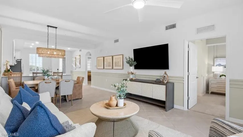 Living room with light tile patterned floors, arched walkways, and ceiling fan
