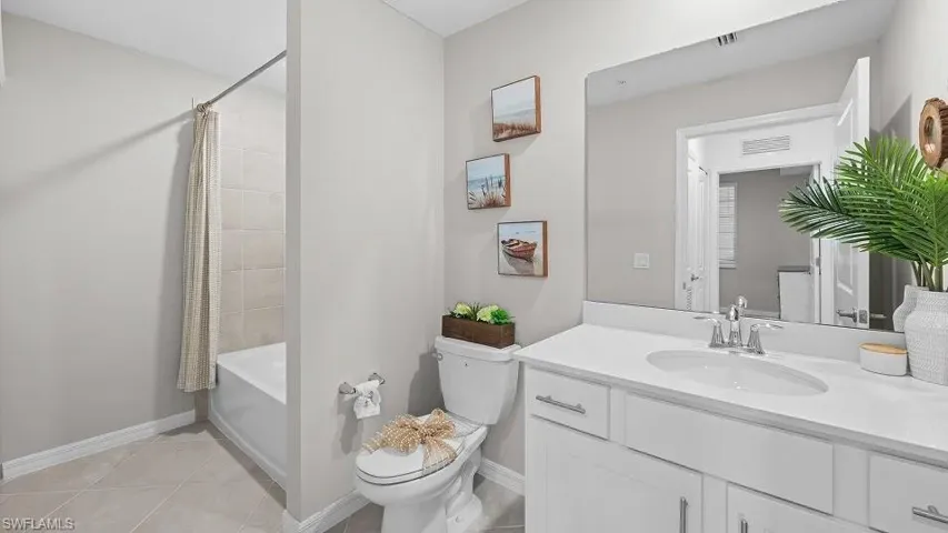 Full bath featuring vanity, shower / tub combo, and light tile patterned flooring