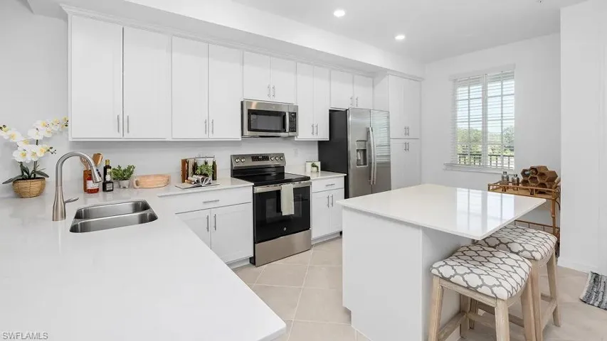Kitchen with stainless steel appliances, a breakfast bar, white cabinetry, a center island, and recessed lighting