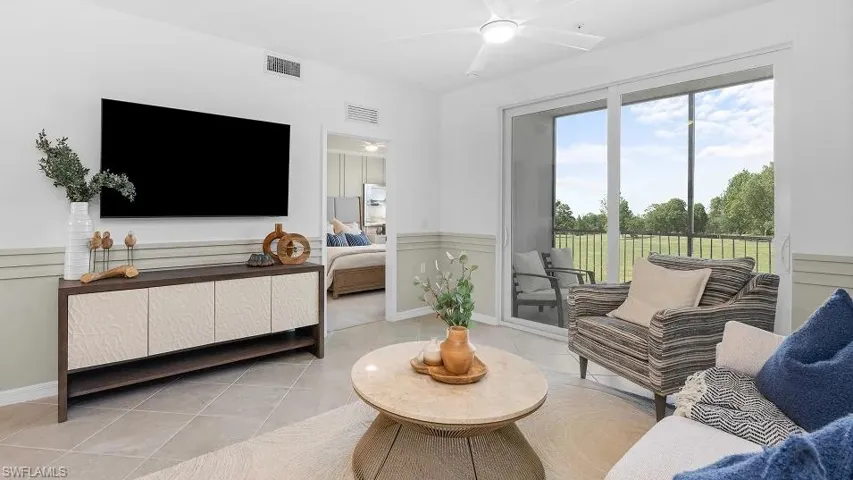 Living room featuring a wainscoted wall, light tile patterned floors, and a ceiling fan