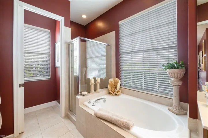 Full bath featuring a stall shower, light tile patterned floors, and a garden tub