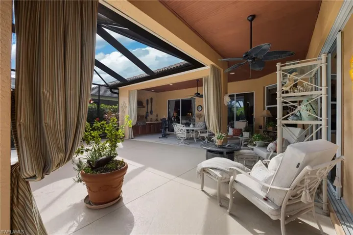 View of patio with glass enclosure, outdoor dining area, and ceiling fan