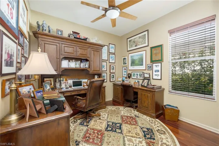 Office featuring dark wood-style floors, ceiling fan, and built in desk
