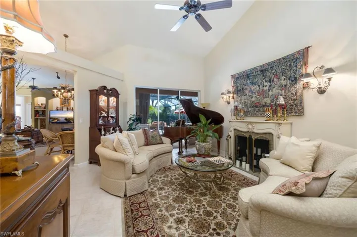 Living area featuring a ceiling fan, a fireplace, and lofted ceiling