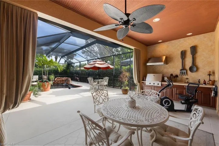 View of patio / terrace with glass enclosure, ceiling fan, a sunroom, and an outdoor kitchen / dining area