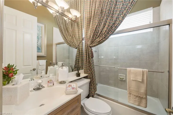 Full bathroom featuring vanity, bath / shower combo with glass door, and hanging lights