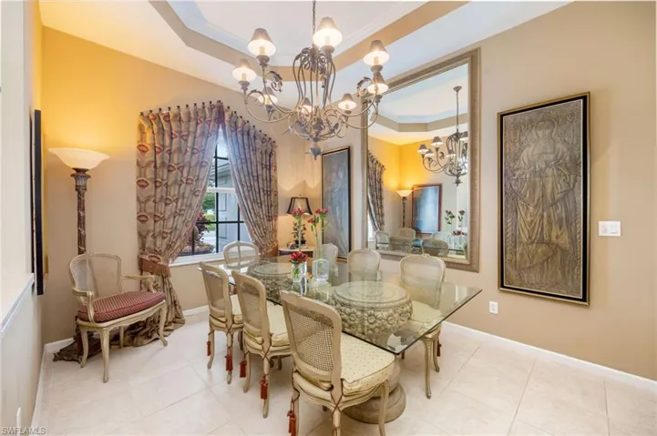 Dining area featuring a tray ceiling, hanging lights, ornamental molding, and light tile patterned floors