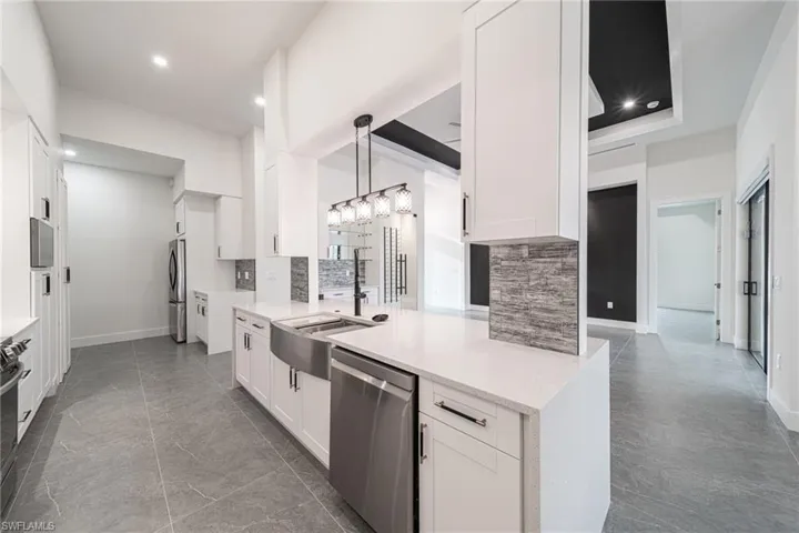 Kitchen with white cabinets, appliances with stainless steel finishes, tasteful backsplash, and pendant lighting