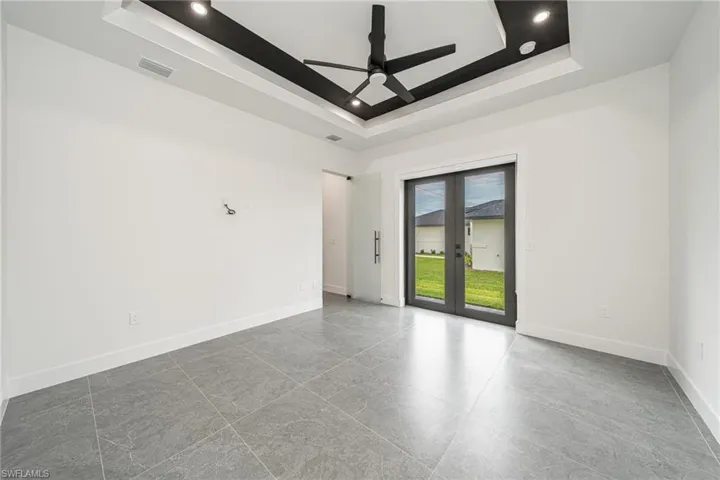 Unfurnished room with a tray ceiling, ceiling fan, and french doors