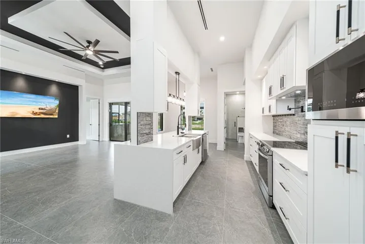 Kitchen with white cabinetry, ceiling fan, decorative light fixtures, and appliances with stainless steel finishes