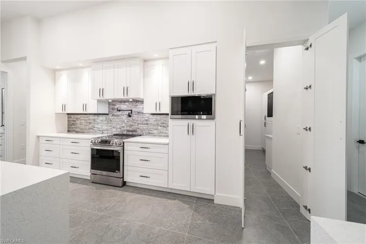 Kitchen with decorative backsplash, stainless steel range oven, white cabinetry, and built in microwave