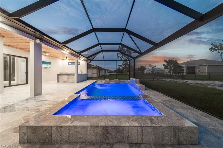 Pool at dusk featuring an in ground hot tub, a lanai, pool water feature, a patio area, and a yard