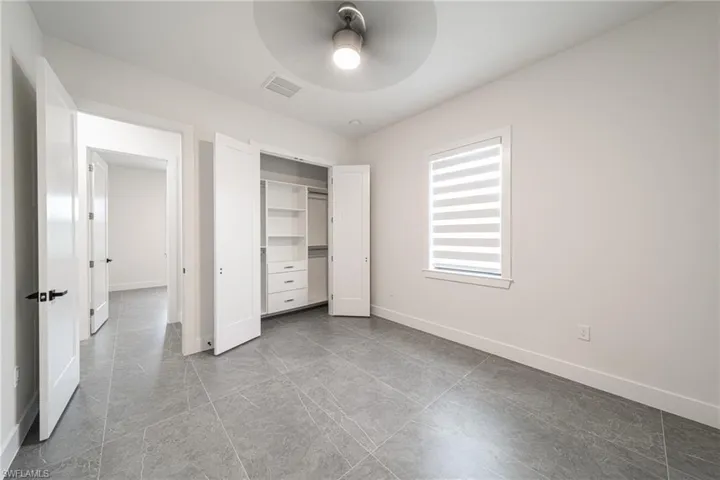 Unfurnished bedroom with ceiling fan and a closet