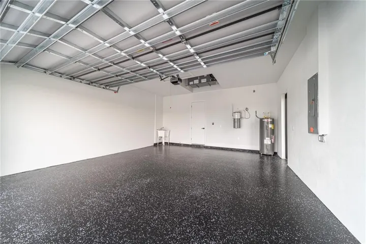 Garage with electric panel, electric water heater, and a garage door opener