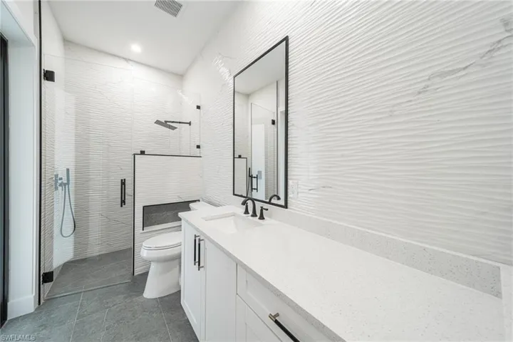Bathroom with vanity, an enclosed shower, and toilet