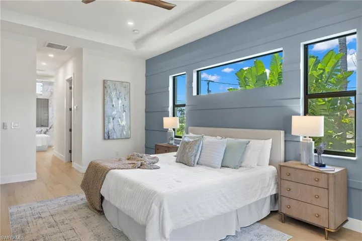 Bedroom with ensuite bathroom, ceiling fan, and light wood-type flooring