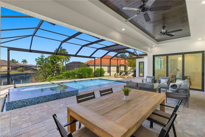View of swimming pool with a patio area, ceiling fan, an in ground hot tub, a lanai, and an outdoor living space