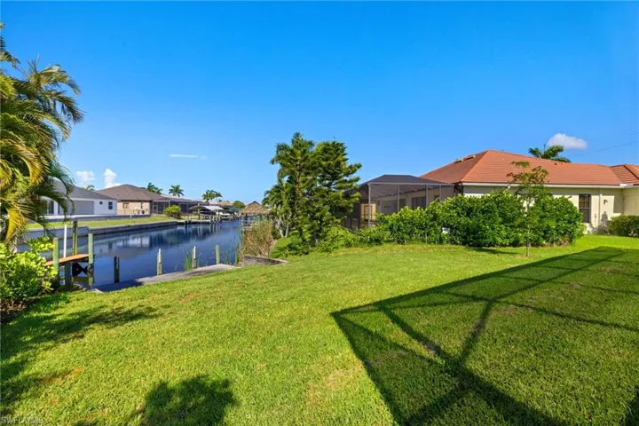View of yard with a dock, a water view, and glass enclosure