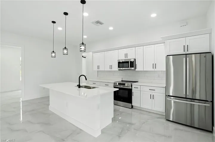 Kitchen with backsplash, stainless steel appliances, light marble finish flooring, white cabinetry, and light stone counters