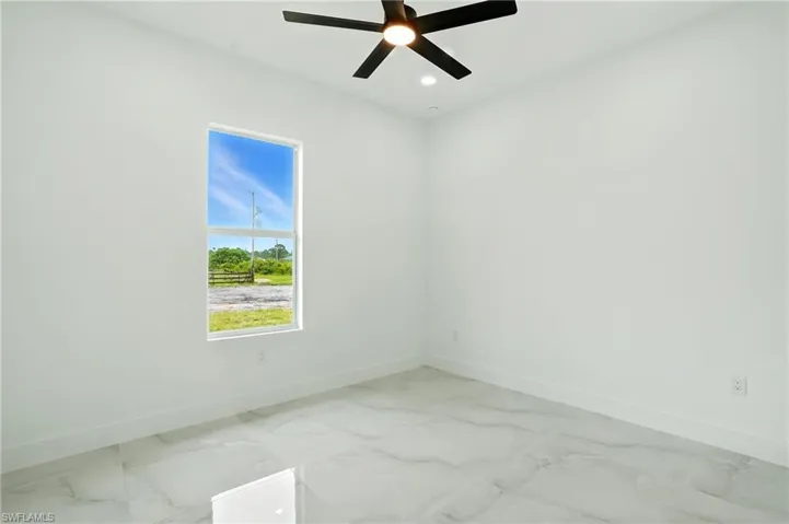Empty room with light marble finish floors and a ceiling fan