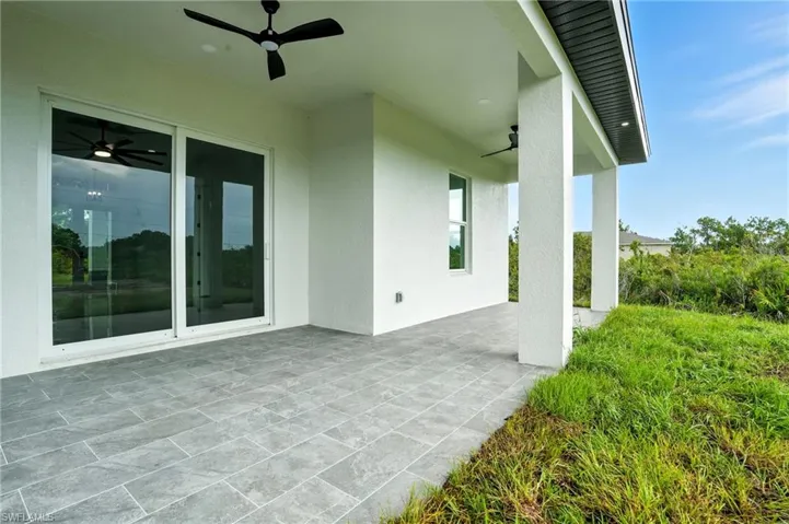 Rear view of property with stucco siding, a yard, and a patio area