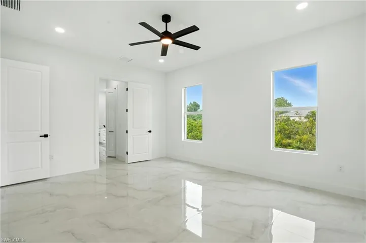 Spare room with light marble finish floors, a chandelier, recessed lighting, and ceiling fan