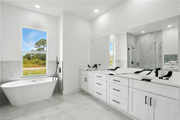 Kitchen with light marble finish floors, white cabinetry, open floor plan, light stone counters, and recessed lighting