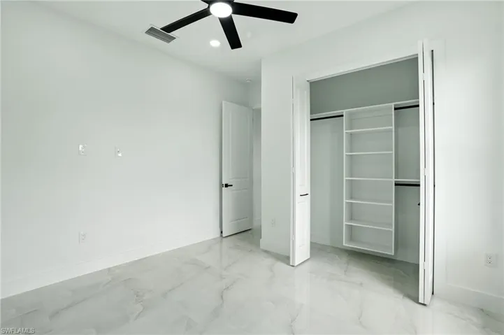 Kitchen with appliances with stainless steel finishes, tasteful backsplash, light marble finish floors, white cabinetry, and light stone countertops