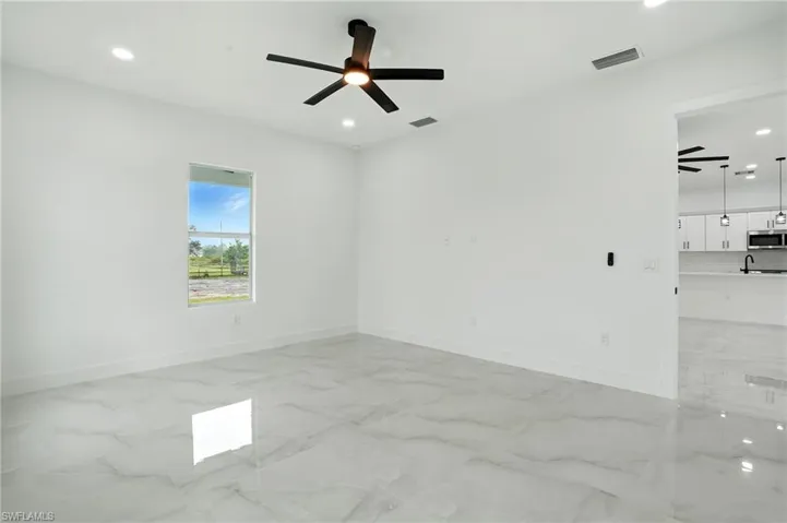 Empty room featuring ceiling fan, light marble finish flooring, and recessed lighting
