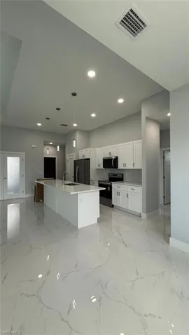Kitchen featuring white cabinetry, a large island with sink, decorative light fixtures, appliances with stainless steel finishes, and recessed lighting