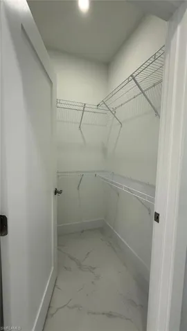 Walk in closet featuring light marble finish floors