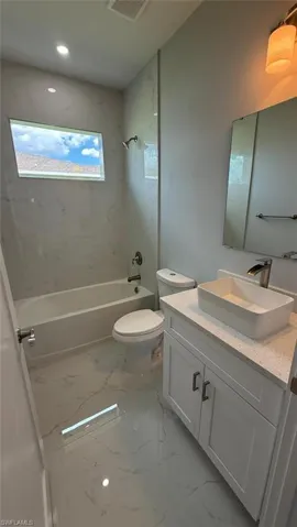 Full bath featuring tub / shower combination, vanity, light marble finish floors, and recessed lighting