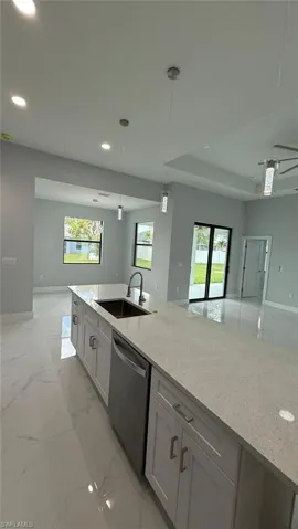 Kitchen featuring light stone counters, open floor plan, hanging light fixtures, and recessed lighting