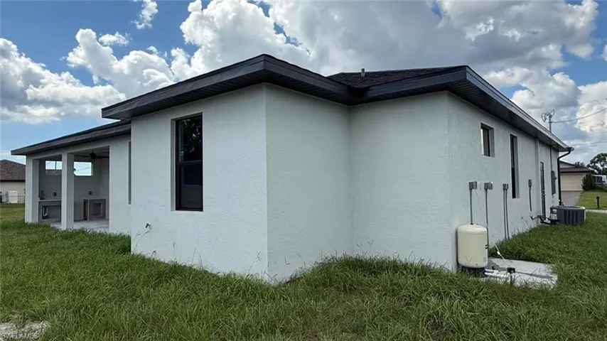 View of side of property with a yard, stucco siding, a patio, and a ceiling fan