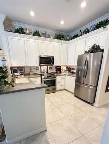 Kitchen featuring appliances with stainless steel finishes, white cabinetry, ornamental molding, a peninsula, and recessed lighting