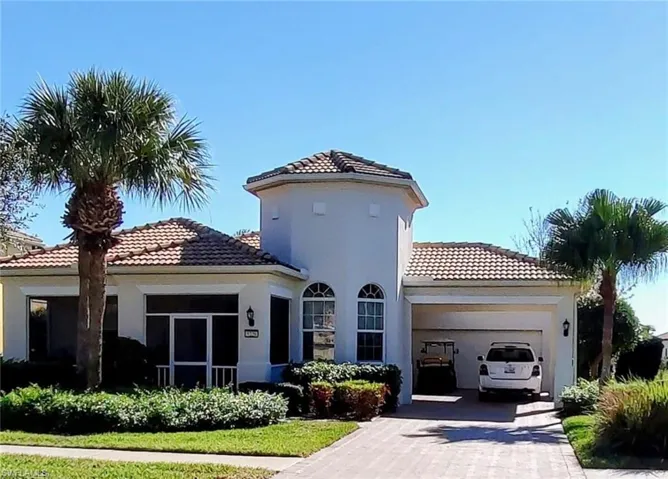Back of property featuring a garage, stucco siding, decorative driveway, and a tiled roof