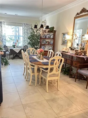 Dining space featuring crown molding, light tile patterned flooring, and a chandelier