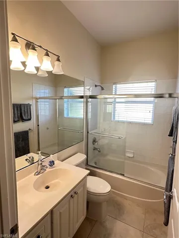 Full bathroom with vanity, combined bath / shower with glass door, and light tile patterned floors