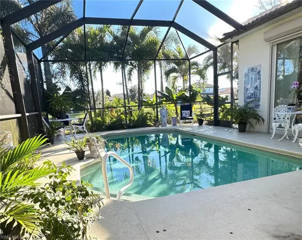 Swimming pool featuring a patio area, glass enclosure, and a sunroom