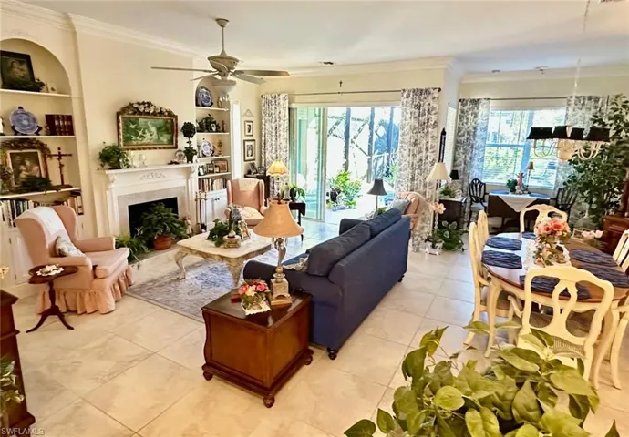 Living area featuring built in shelves, crown molding, plenty of natural light, light tile patterned flooring, and a fireplace with flush hearth