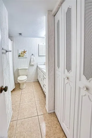Full bathroom with vanity, a closet, light tile patterned flooring, and a shower with shower curtain