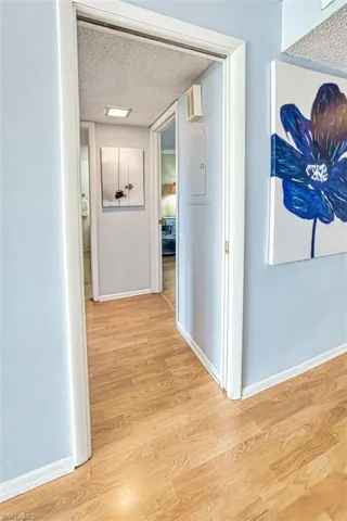 Corridor with a textured ceiling and light wood-type flooring