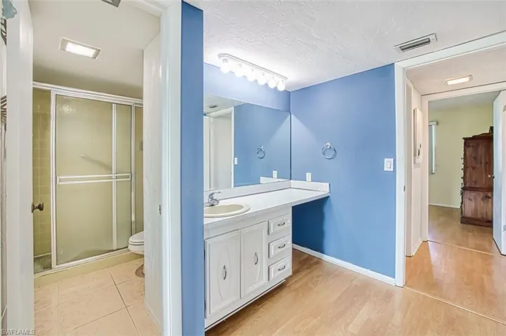 Master Bathroom featuring vanity, a stall shower, a textured ceiling, and light wood-style flooring