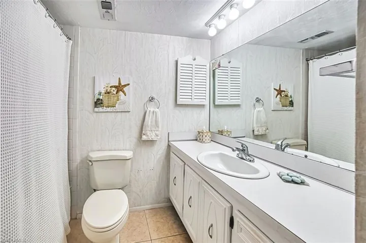 Bathroom featuring a shower with curtain, a textured ceiling, vanity, and light tile patterned flooring