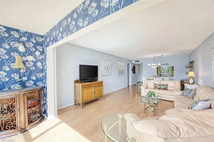 Living area featuring light wood-type flooring, wallpapered walls, and hanging lights