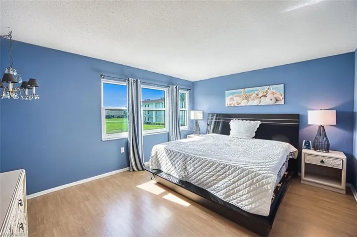 Master Bedroom with light wood finished floors, a textured ceiling, and suspended lighting