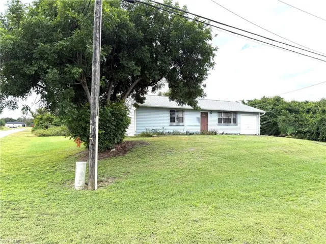 Ranch-style home featuring a front lawn and a garage