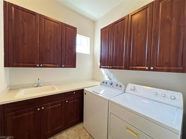 Laundry room with cabinets, washer and dryer, and sink