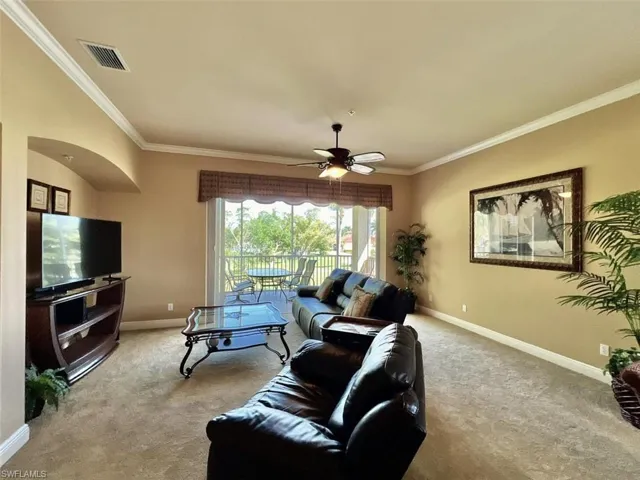 Living room with carpet, ceiling fan, and crown molding. Pocketing glass sliders bring the outdoors in